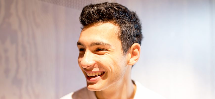 En glatt leende manlig student I studentmatsalen.